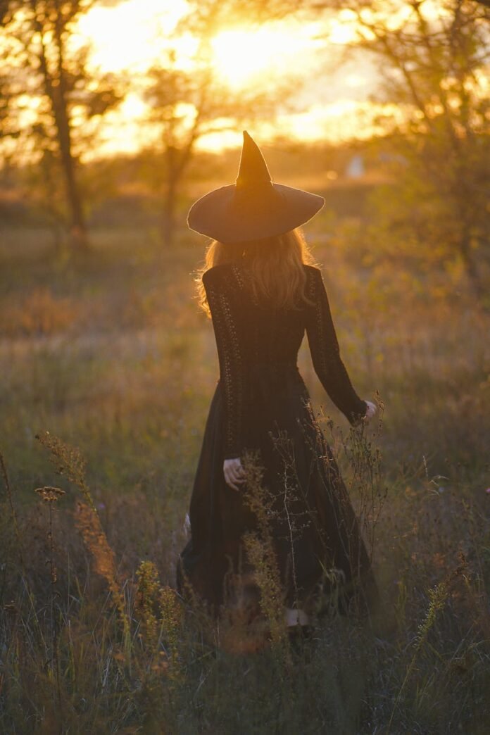 back view of a woman in a halloween witch costume walking on a field