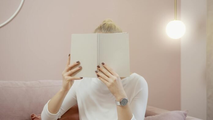 woman covering her face with a notebook