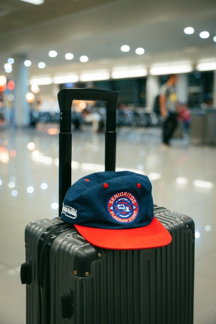 stylish cap on suitcase at airport terminal