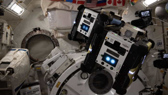 Na imagem, dois robôs auxiliares Astrobee, em modo de voo livre, são vistos dentro do módulo laboratorial Kibo. Os robôs foram projetados para ajudar as tripulações a bordo da Estação Espacial Internacional a concluir tarefas diárias e reduzir o tempo gasto em atividades rotineiras.