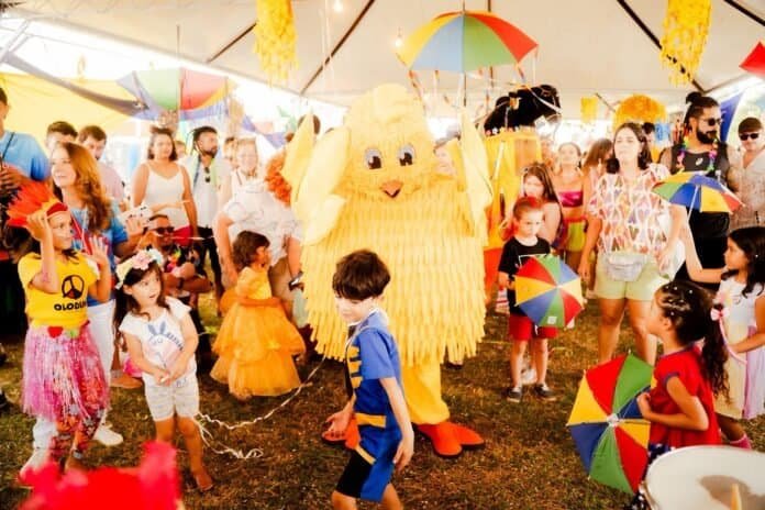 Personagem de festa infantil com fantasia de pato amarelo em evento ao ar livre.
