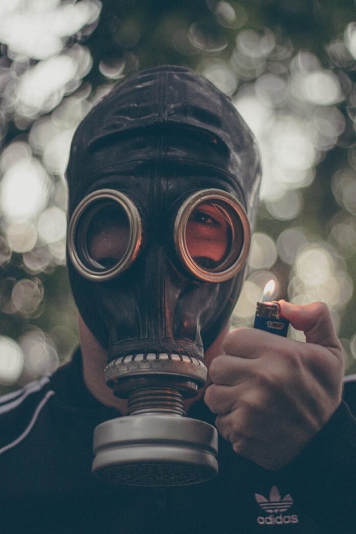 close up shot of a person wearing a gas mask holding a lighter
