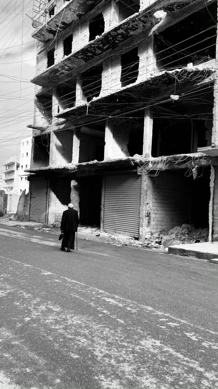 man passing by ruins of residential building