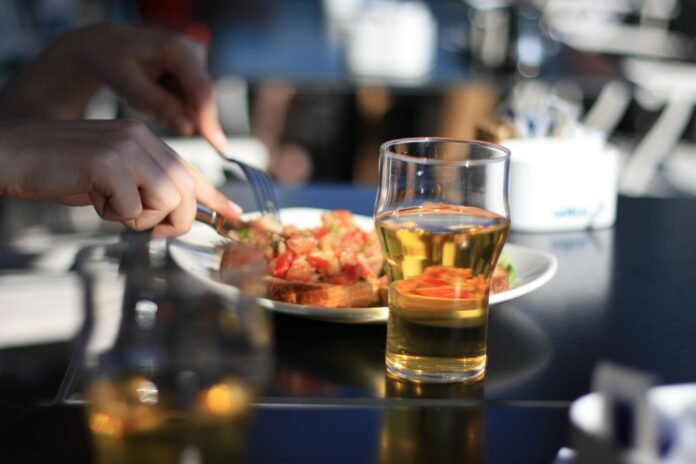pilsner glass with beer beside white plate