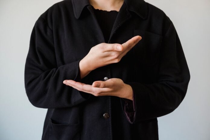 close up of person in coat making hand gesture