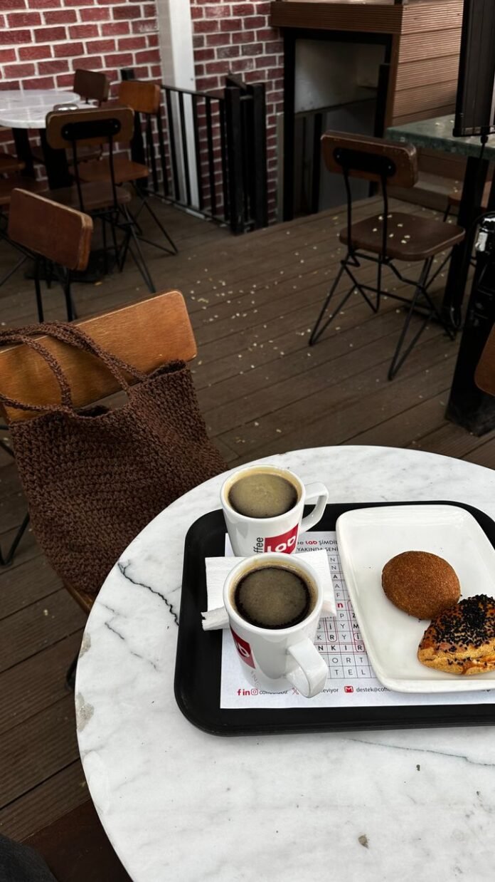 a table with two cups of coffee and a bag of donuts
